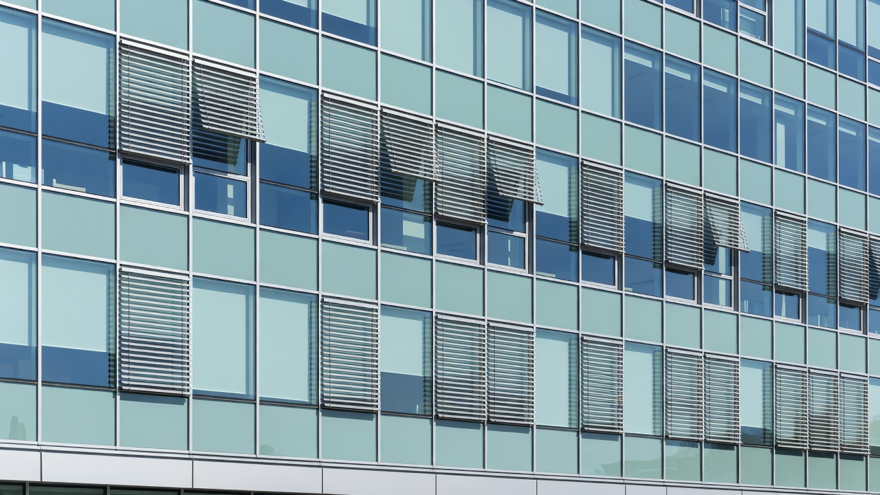 Daylit glazed building elevation with repeated window bays and visible façade shading